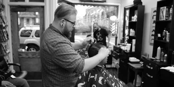 Barber cutting a customer's hair inside a barbershop.