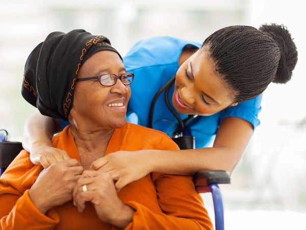 Nurse warmly caring for an elderly woman in a wheelchair.