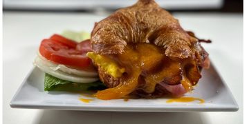 Delicious croissant with smoked ham, bacon, cheese and optional lettuce, tomato, and onions