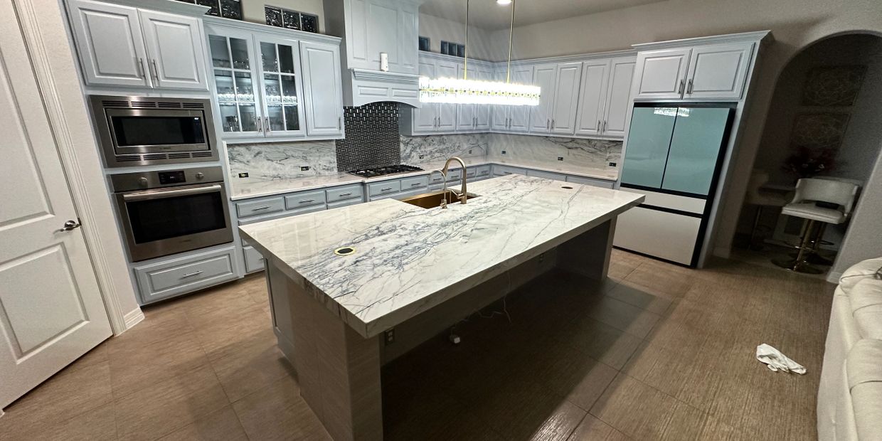 Modern kitchen with marble countertops and white cabinetry.
