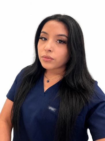 Confident woman in navy blue scrubs with long black hair.
