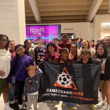 Group photo of diverse fans holding a Gamechangers banner at Dallas Trinity FC event.