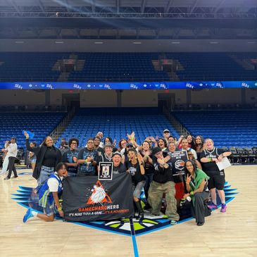 Group photo of happy basketball players and supporters on court.