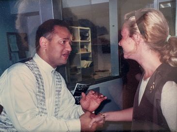 Two people engaged in a handshake and conversation indoors.