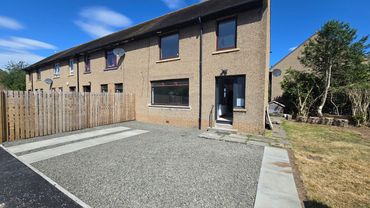 Modern townhouse with gravel driveway and fenced yard.