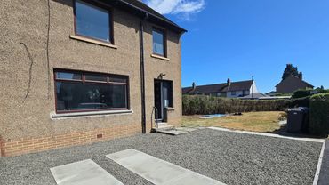 Exterior of a house with pebble driveway and garden.