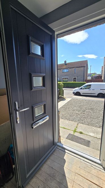 Open black front door with view of the street and white van.