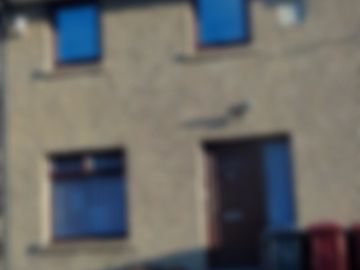 Blurred image of a building facade with windows and a door.