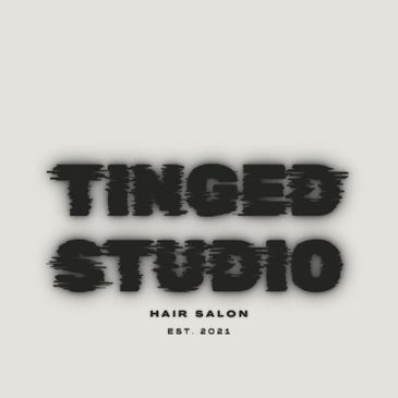 Blurred black text logo of Tinged Studio Hair Salon on gray background.