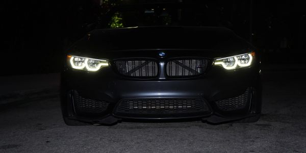 Front view of a black BMW with headlights on at night.