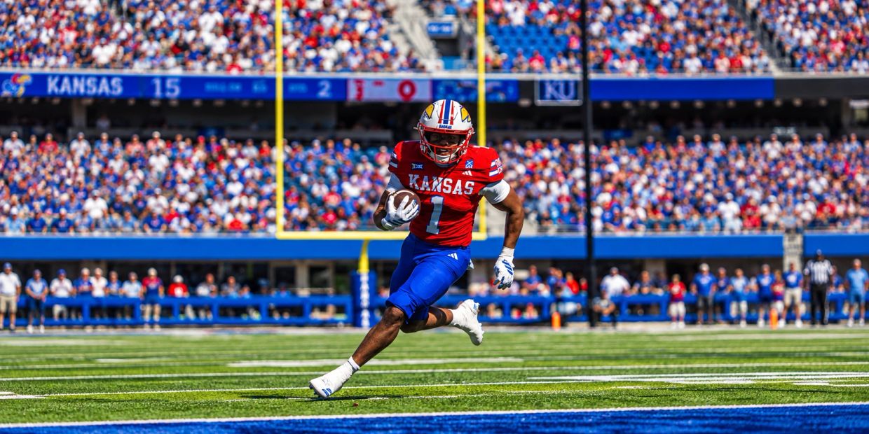 Kansas football player running with the ball towards the end zone.