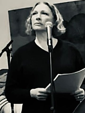 Woman speaking into a microphone while holding papers.