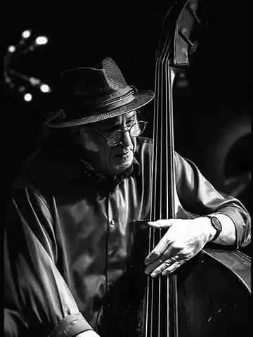 Black and white photo of a man playing double bass with focus and passion.