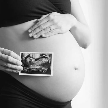 Pregnant woman holding an ultrasound image over her belly.