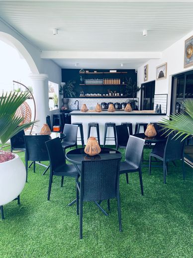 Modern outdoor cafe seating with black chairs and green artificial turf.