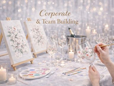 Person painting floral designs on wine glasses for corporate team building.