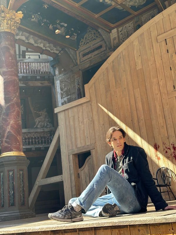 Alex Hatcher sitting on the stage at the Shakespeare's Globe Theatre in London