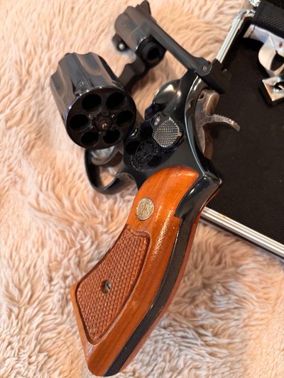 Close-up of a revolver with wooden grip on a soft surface.