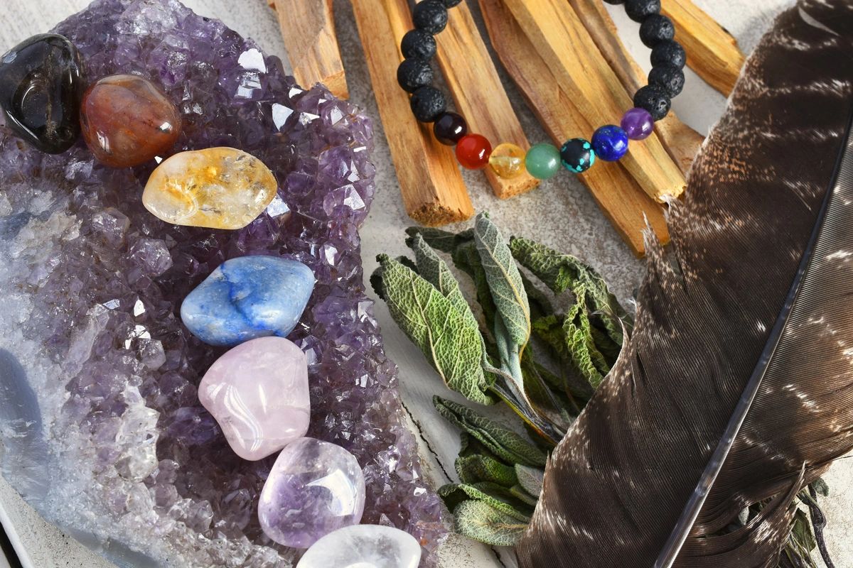 Chakra colored gemstones laying on a large amethyst geode.  A lava bead bracelet near by.