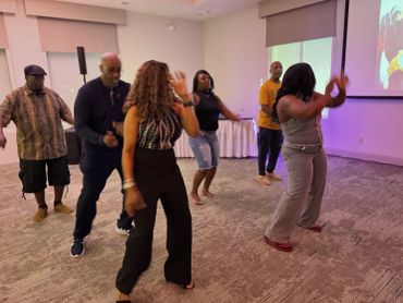 A group of six people dancing indoors in a casual setting.