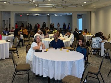 People seated at round tables in a spacious conference room.