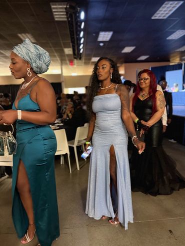 Three women in elegant evening gowns at a formal event.