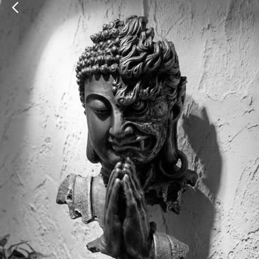 Artistic wall sculpture combining serene Buddha and fierce demon faces.
