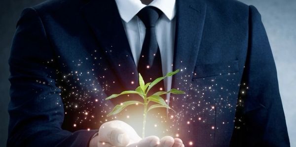 Businessman holding a glowing plant symbolizing growth and innovation.