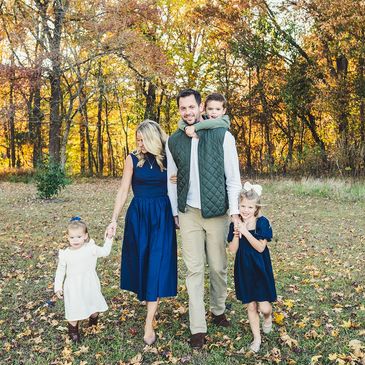 A family of five walking together outdoors in autumn.