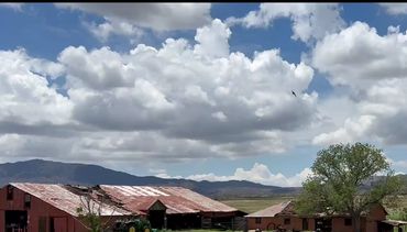 Rustic farm buildings under a cloudy sky.