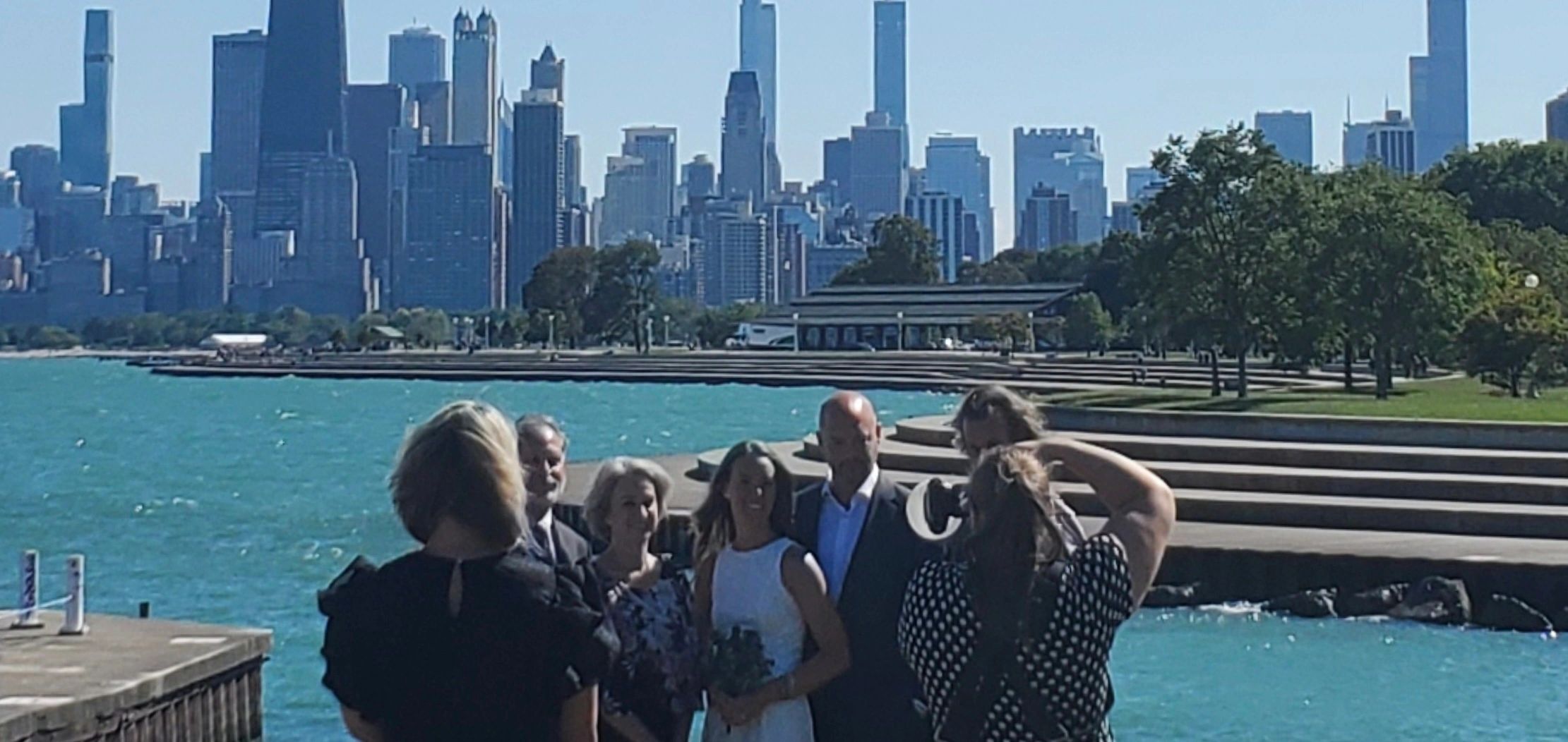 Group photoshoot by the water with city skyline in the background.