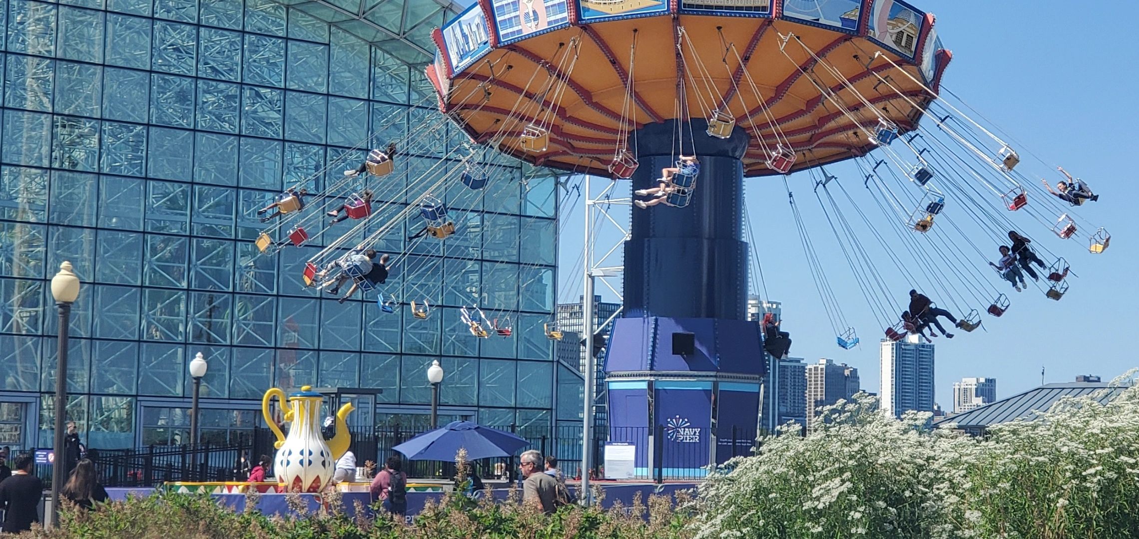 People enjoying a swing ride at Navy Pier beneath clear blue sky.