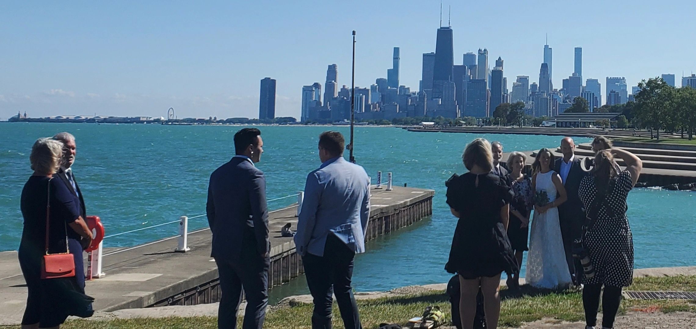 People gathered near the water with a city skyline in the background.