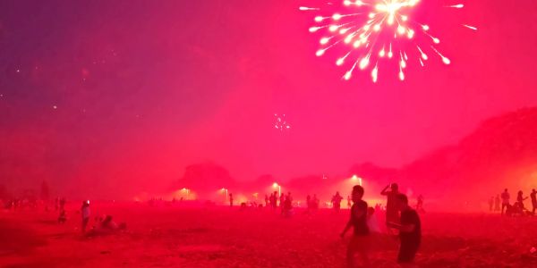 People watching fireworks in a red-lit area.