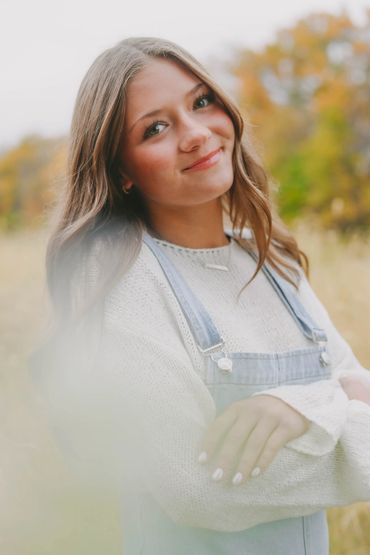 Young woman smiling outdoors in autumn with soft focus.