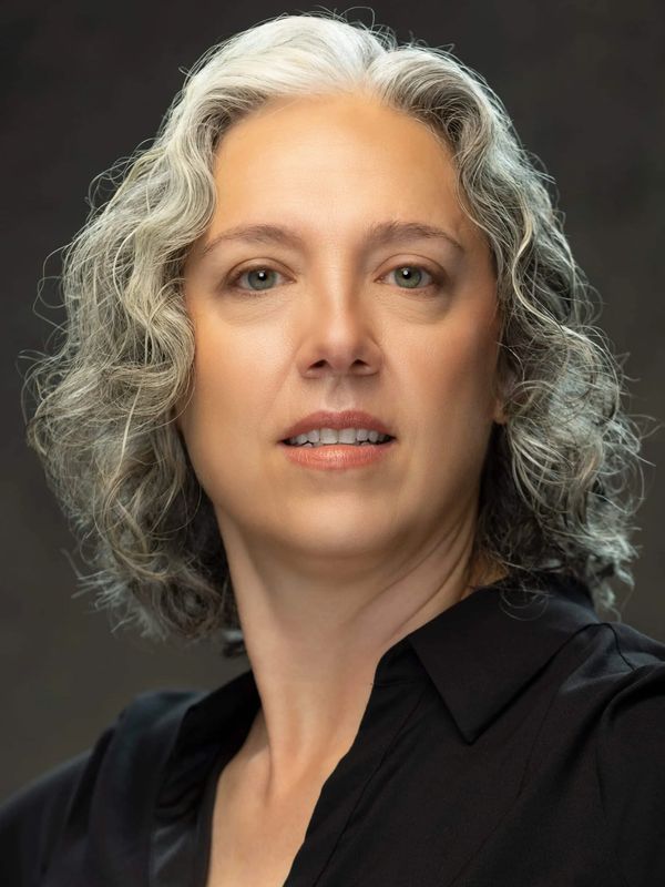 Portrait of a woman with curly gray hair.