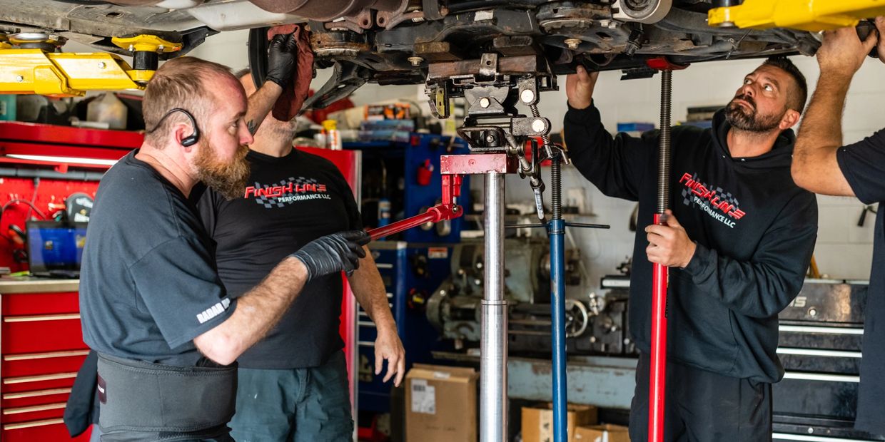 Finish Line employees looking at undercarriage of car holding various tools