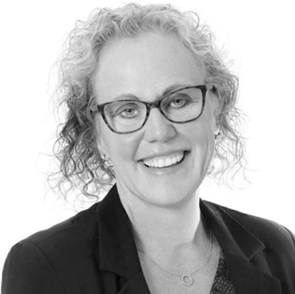 Smiling woman with glasses and curly hair.