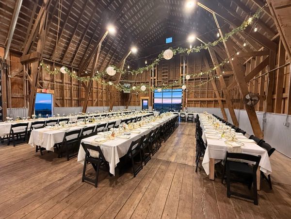 Long barn interior set up with tables and chairs for an event.