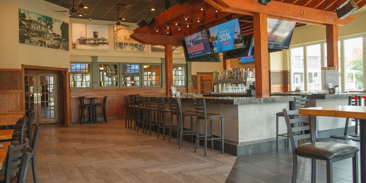 Empty modern bar with wooden beams and multiple TVs.