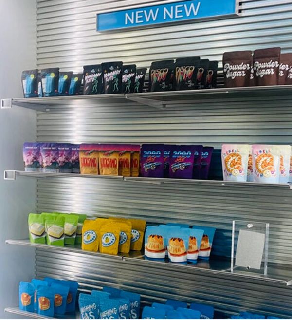 Shelves displaying various colorful packaged products under a 'NEW NEW' sign.