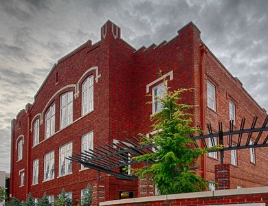 Red brick building with large windows under a cloudy sky.
