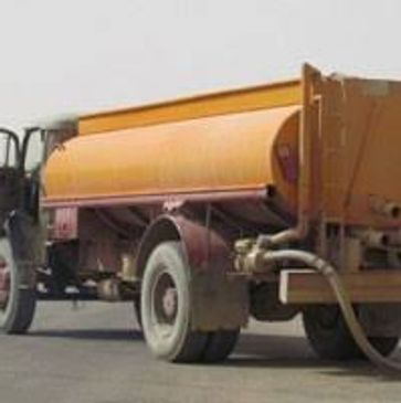 An orange water tanker truck unloading water.