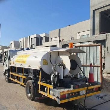 A water tanker truck parked outside modern buildings.
