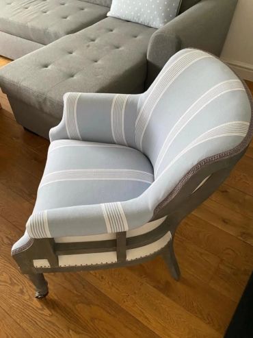 Elegant striped armchair with wooden legs on a wooden floor.