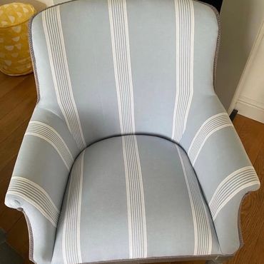 Light blue armchair with white vertical stripes on wooden floor.