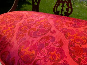 Close-up of a red and orange patterned fabric upholstery on a chair.