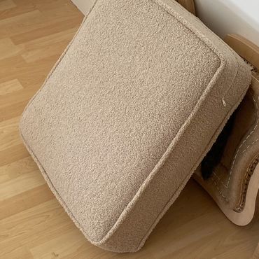 Beige cushioned chair cover leaning against a wooden chair frame.