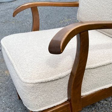 Close-up of a cushioned wooden armchair with beige upholstery.