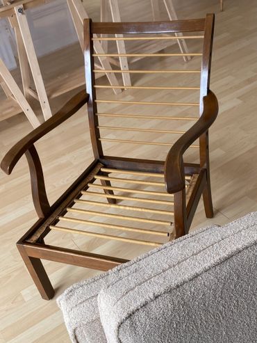 Wooden chair frame without cushions, showing slats for support.